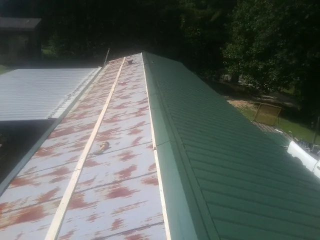 Old rusted panels beside newly installed green metal roofing — Wind Damage Roof Repair by Roofing Brothers in Seeley Lake
