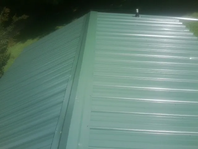 New green metal panels meeting at the ridge of a roof — Flat Roof Repair work by our crew in Seeley Lake
