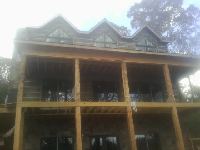 Dormers and porch framing on a large log home under construction — Roof Coating work by our crew in Seeley Lake