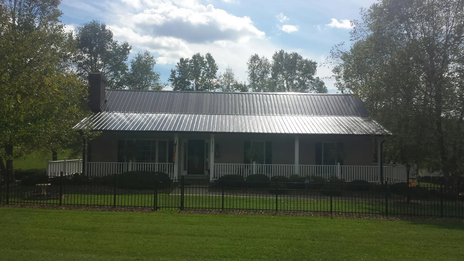 Gray metal roof on a brick ranch with a full width front porch — Gutter Guard Installation work by our crew in Seeley Lake