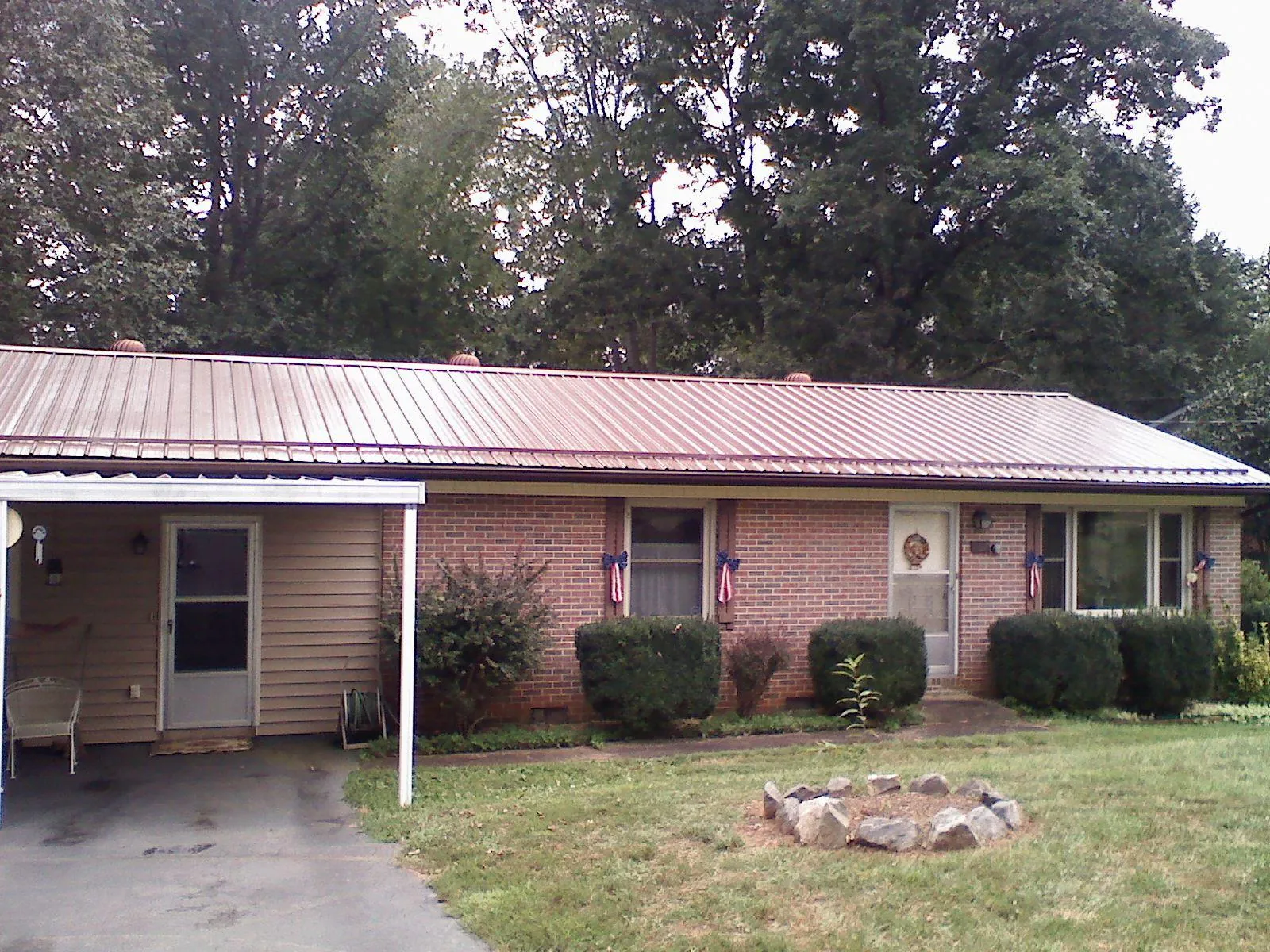 Bronze metal roof and carport on a brick ranch home — Roof Repair work by our crew in Seeley Lake