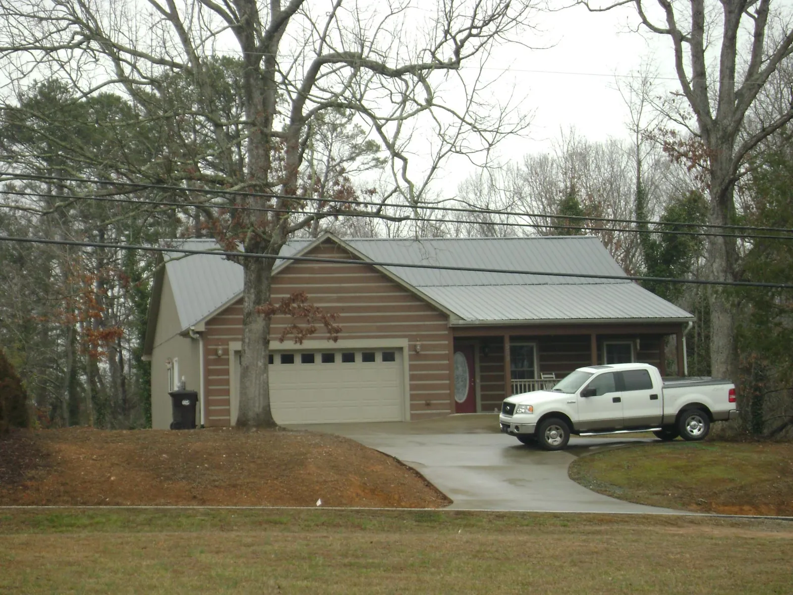 Gray metal roof on a log sided house with an attached two car garage in Seeley Lake