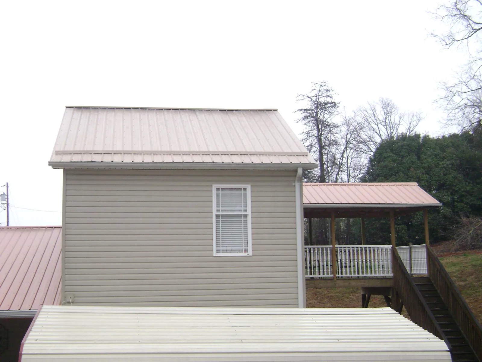Tan metal roofs on a two story addition and attached porch, from a Roof Replacement job in Seeley Lake