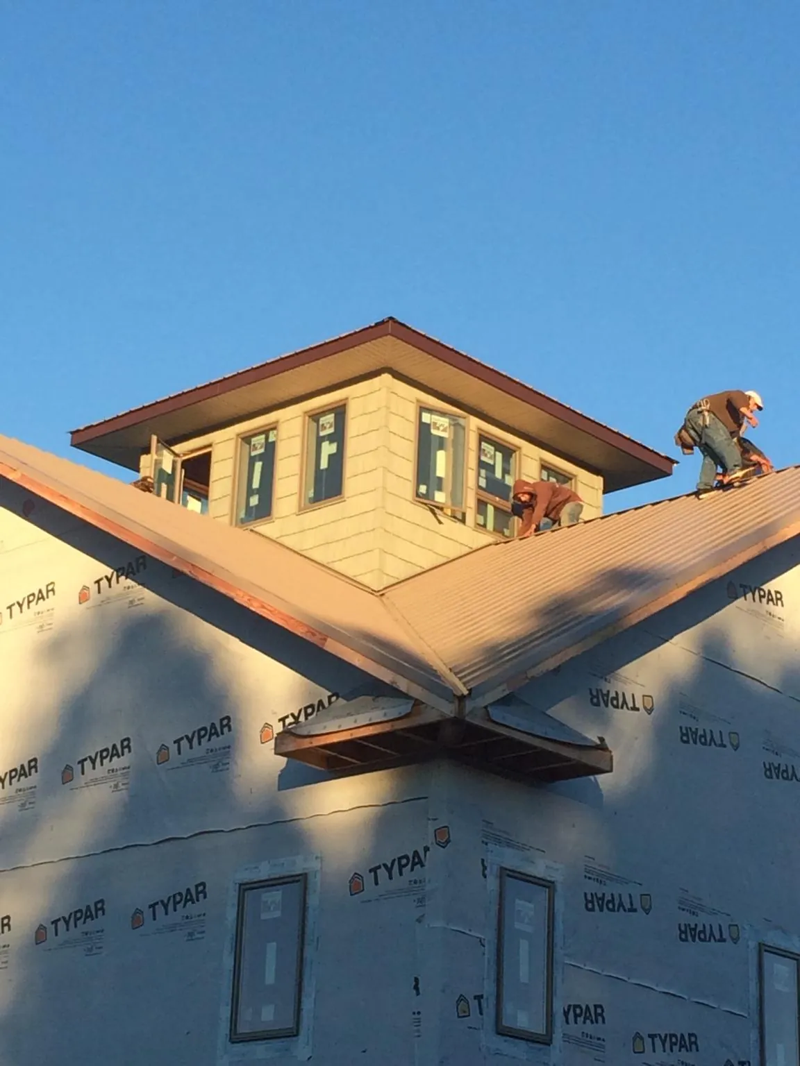 Roofers working around a rooftop cupola on a new metal roof at sunset — Roof Waterproofing in Seeley Lake by Roofing Brothers